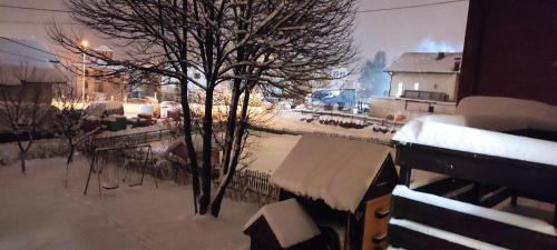 a tree covered in snow next to a building at Apartman MiMa in Pale