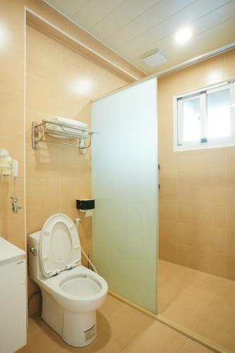 a bathroom with a toilet and a glass shower door at Miruku Homestay in Taitung City