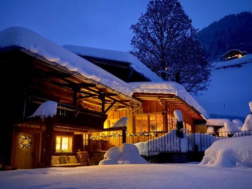 een huis bedekt met sneeuw 's nachts met lichten bij Berglodge Ascharina in Sankt Antönien