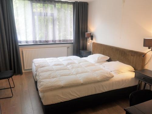 a bed in a room with a large window at DBO81 Spacious apartment in the center and beach nearby in Domburg