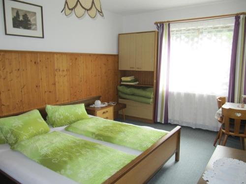 een slaapkamer met een bed met groene lakens en een raam bij Ferienwohnung Wörndl in Faistenau