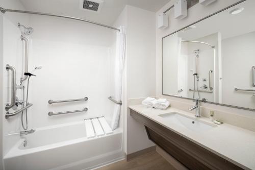a bathroom with a tub and a sink and a mirror at WoodSpring Suites Seattle Redmond in Redmond