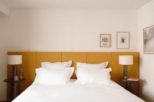 a bedroom with a bed with white pillows and two lamps at Le Val Thorens, a Beaumier hotel in Val Thorens
