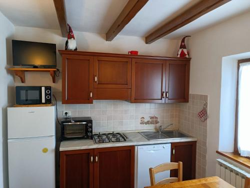 cocina con armarios de madera y nevera blanca en Cottage Abetone La Capanna in Tuscany, en Abetone