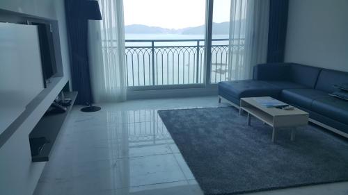a living room with a blue couch and a large window at Ocean View in Geoje 