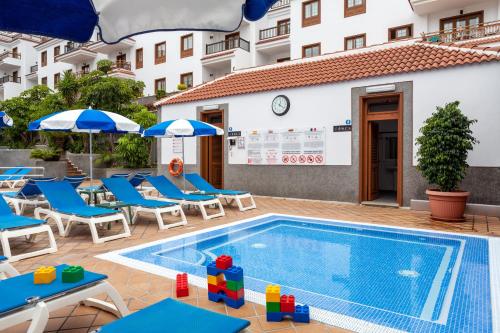 una piscina con sillas y sombrillas junto a un hotel en Apartamentos Casablanca, en Puerto de la Cruz