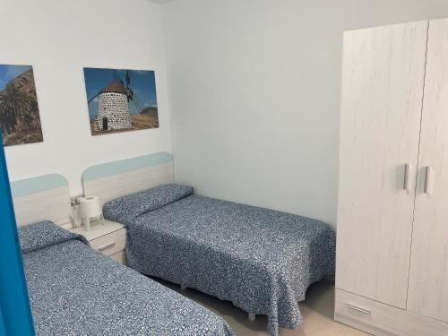 1 dormitorio con 2 camas y armario blanco en Apartamentos Tao Noah, en Puerto del Rosario