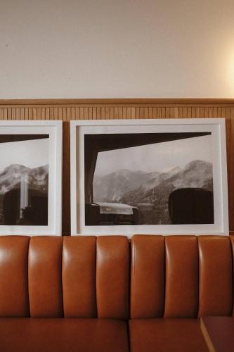 two framed pictures on a wall above a couch at Le Val Thorens, a Beaumier hotel in Val Thorens