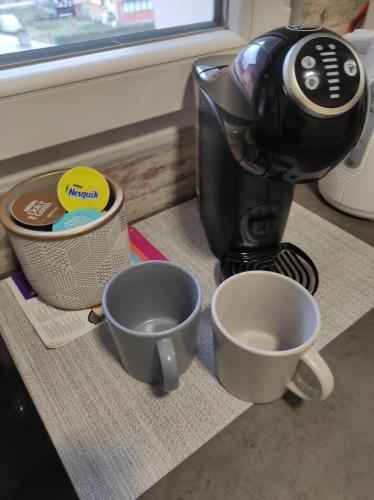 a coffee maker sitting next to two cups on a counter at Apartman Petrov in Donji Milanovac