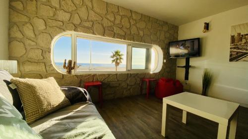 a living room with a stone wall and a window at "Méditerranée" Salon vue mer au coeur de la ville 10m de la plage in Canet-en-Roussillon