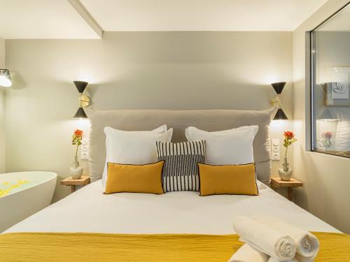 une chambre avec un grand lit blanc avec des oreillers orange dans l'établissement Fabulous Grey, à Paris