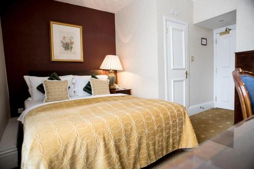a hotel room with a bed with a yellow bedspread at The Colonnade in London