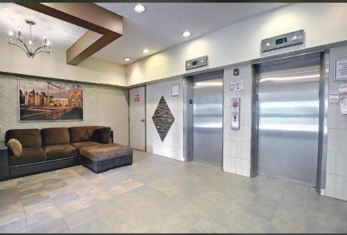 a lobby with a couch and two elevators in a building at Downtown River Valley Bachelor Suite Condo, NON Smoking, 12 inches Queen Bed, Beautiful Minimalist, very convenient every where in Edmonton