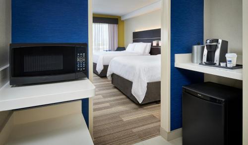 a hotel room with a bed and a microwave at Holiday Inn Express & Suites Windsor East - Lakeshore, an IHG Hotel in Saint Clair Beach