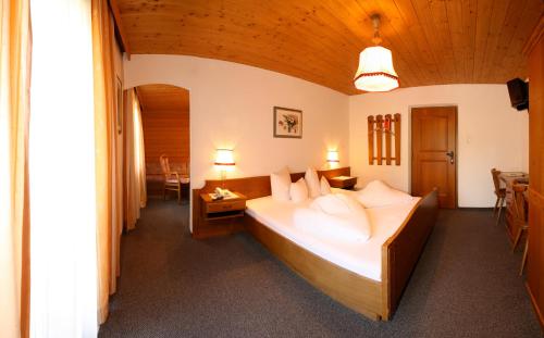 ein Schlafzimmer mit einem großen Bett, einem Tisch und Stühlen in der Unterkunft Pension Tirol in Nauders