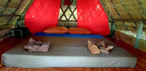 a bed in a red tent with shoes on it at Crusoe Koh Takiev Island in Koh Ta Kiev