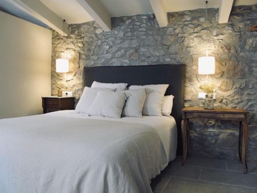1 dormitorio con 1 cama grande y pared de piedra en CAN SAFRA, en La Pera