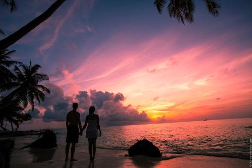 a couple standing on the beach watching the sunset at Stingray Beach Inn in Maafushi