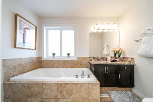 a large bath tub in a bathroom with a window at Mediterranean Retreat - King Bed - Fireplace - Garage in Edmonton