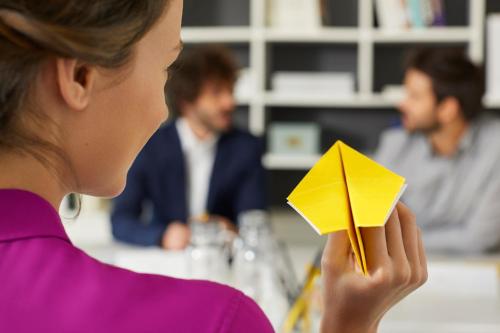 a woman holding a yellow paper plane in her hand at Golden Tulip Marseille Euromed in Marseille