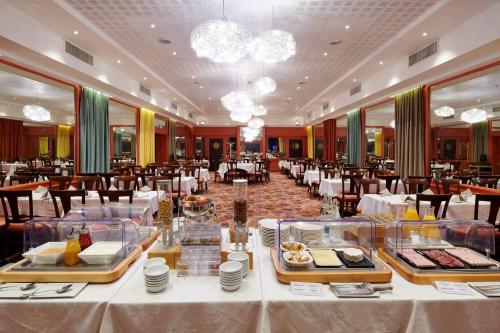 a restaurant with white tables and chairs and food on display at Hotel Vacances Bleues Provinces Opera in Paris