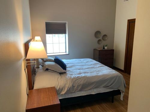 a bedroom with a bed with a lamp and a window at Stylish ground level apartment close to everything in Rapid City