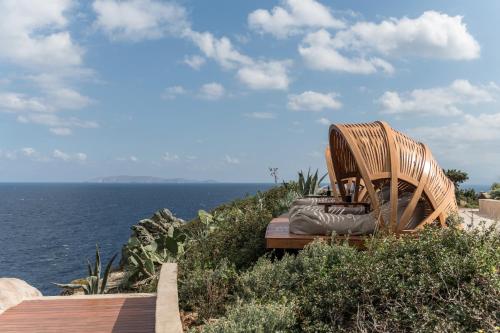 a wooden bench sitting on the side of the ocean at Acro Suites - A Wellbeing Resort in Agia Pelagia