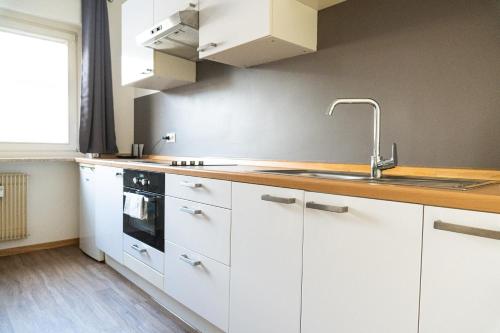 a kitchen with white cabinets and a sink at Flow Apartments Piave in Merano