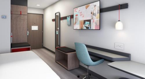 a hospital room with a blue chair and a desk at avid hotels - Macon North by IHG in Macon