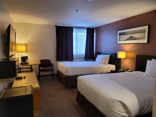 um quarto de hotel com duas camas e uma televisão em Roadking Inns Motel em Calgary