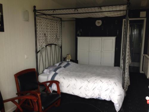 um quarto com uma cama de dossel e uma cadeira em L'Epicurien em Saint-Nicolas-de-Port