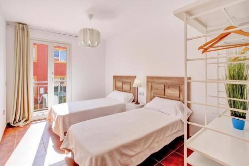 two beds in a white room with a window at Bbq house vila in Corralejo