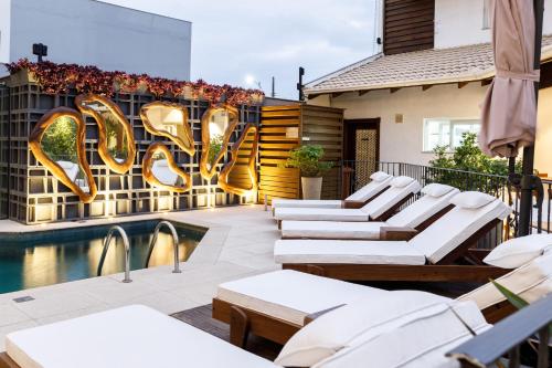 a patio with lounge chairs and a sign that reads love at Villa d'Ozio Hotel e Cucina in Itajaí