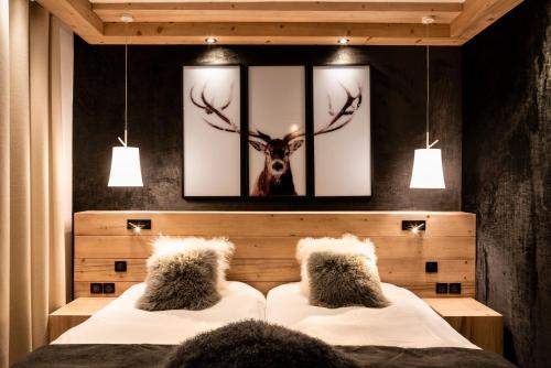 a bedroom with two beds and a picture of a deer at Hotel Les Mélèzes in Les Deux Alpes
