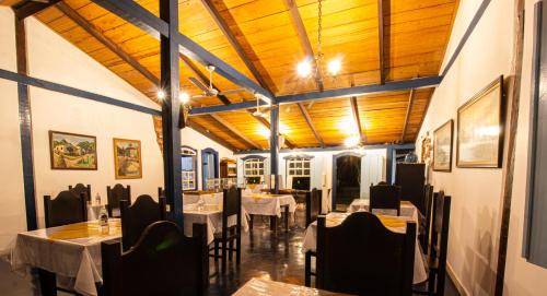 Un comedor con mesas y sillas y techos de madera. en Pousada Villa Bia, en Pirenópolis