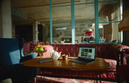 a coffee table with a laptop on a red couch at Ati Ambavi Botique Hotel Gudauri in Gudauri
