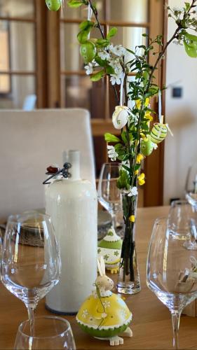 a table with wine glasses and a vase with flowers at Domaine de Cazal - Chambres d'Hôtes avec piscine au cœur de 26 hectares de nature préservée in Saint-Cyprien
