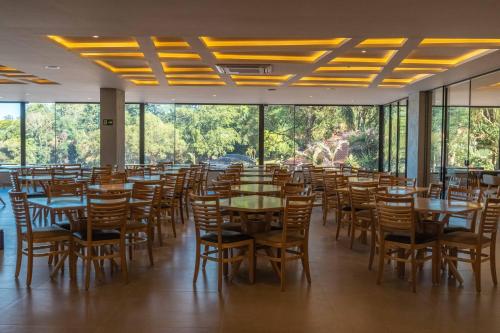 a dining room with tables and chairs and windows at Complexo Eco Cataratas Resort by SJ in Foz do Iguaçu