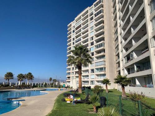 a large apartment building next to a swimming pool at Primera línea frente al mar, con gran piscina. in Coquimbo