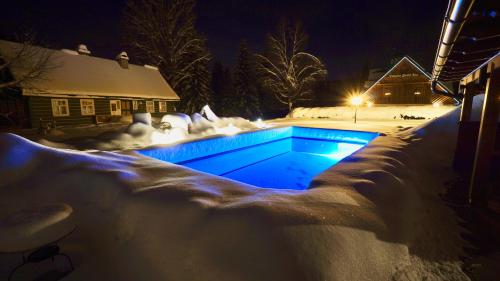 a swimming pool covered in snow at night at Chalet Schäfer s vyhřívaným bazénem se slanou vodou in Harrachov
