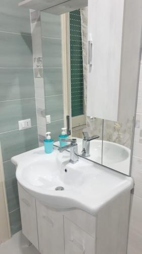 Baño blanco con lavabo y espejo en B&B By the Station, en Battipaglia