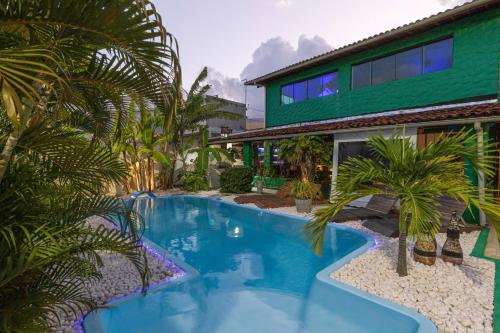 a swimming pool in front of a house with palm trees at Taverna do Paraiso in Janga