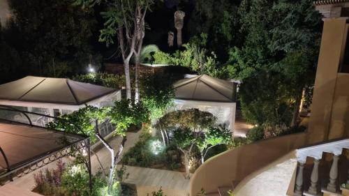 an outdoor garden with umbrellas and trees at night at Kemani Villa Sara Olbia in Olbia