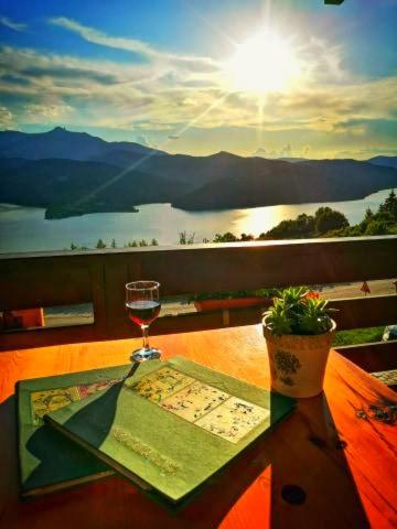 a glass of wine sitting on a table with a view at Pensiunea La Bunica in Rugineşti