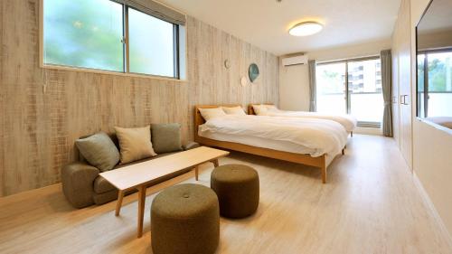 ein Schlafzimmer mit einem Bett, einem Sofa und einem Tisch in der Unterkunft RakutenSTAY x Shamaison Osaka Dekijima - 304 in Osaka