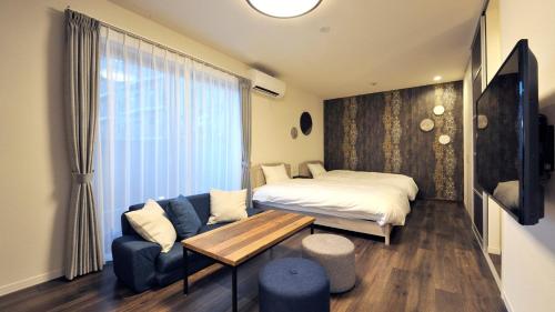 a bedroom with a bed and a couch and a table at RakutenSTAY x Shamaison Osaka Dekijima - 201 in Osaka