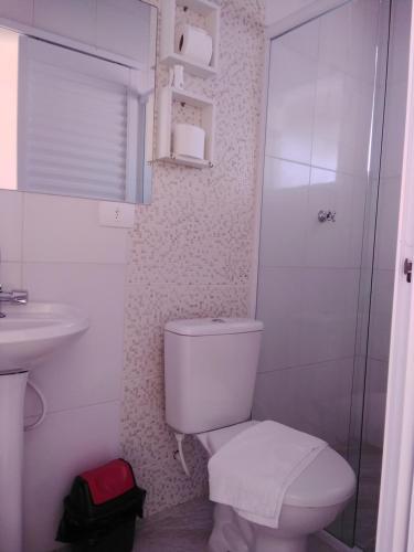 La salle de bains blanche est pourvue de toilettes et d'un lavabo. dans l'établissement Pousada Gotam, à Caraguatatuba