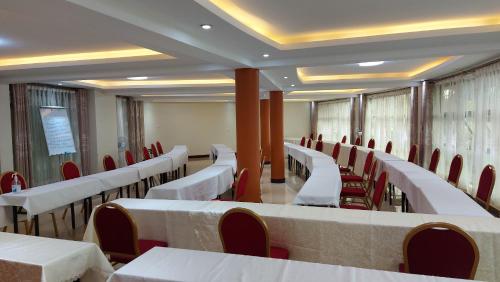 a conference room with white tables and red chairs at Asamar Country Resort in Mbarara