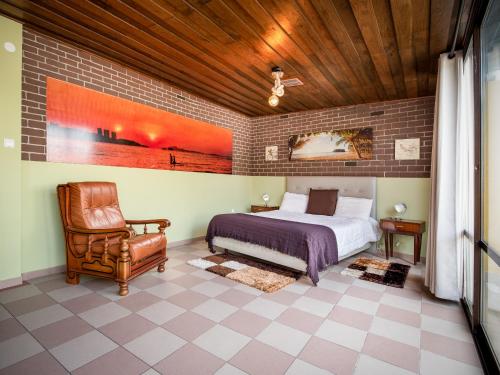 a bedroom with a bed and a chair at HAVANA VINTAGE Alojamentos Quartos in Santiago do Cacém