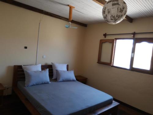 ein Schlafzimmer mit einem Bett mit zwei Kissen und einem Fenster in der Unterkunft Villa Nature in Toliara